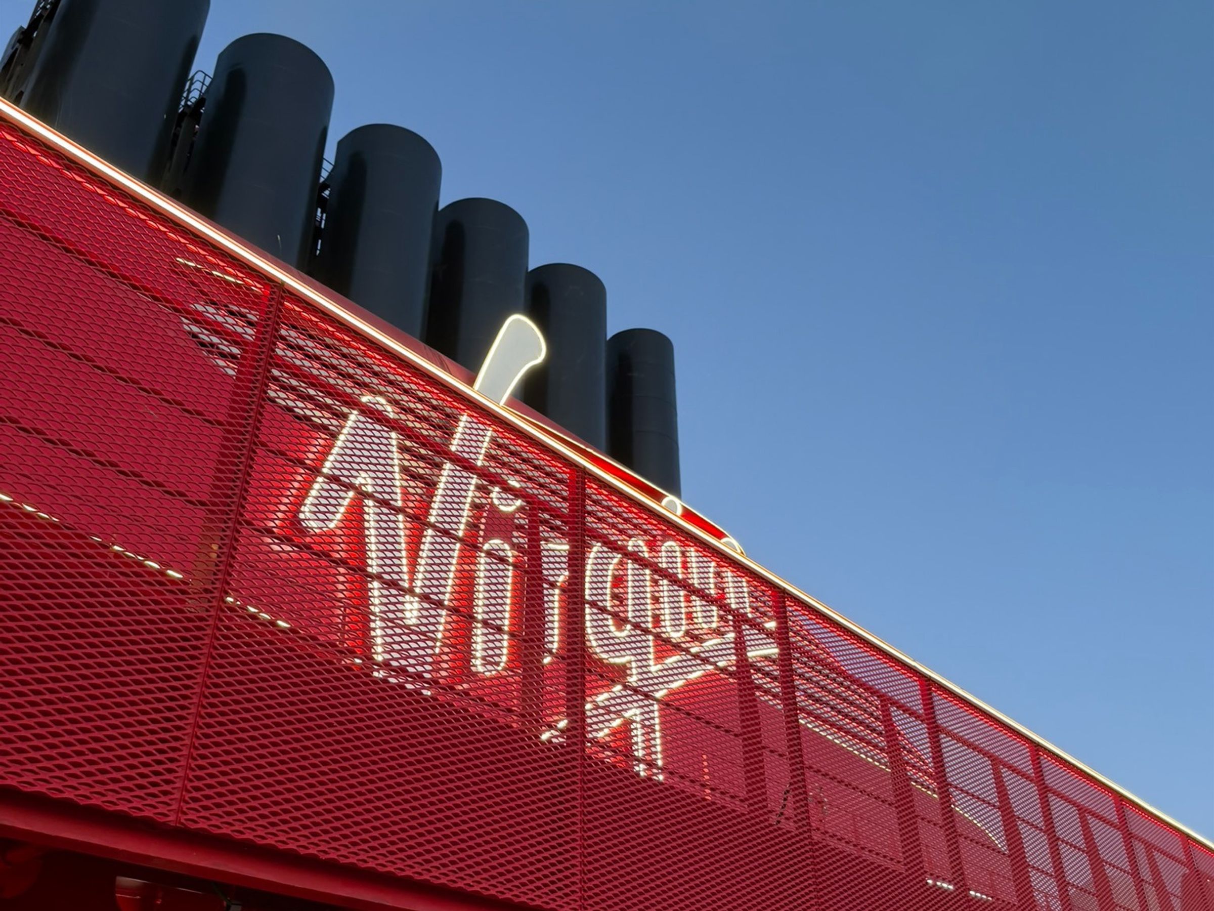 Virgin Voyages Valiant Lady red funnel and Ahoy sign against a blue sky